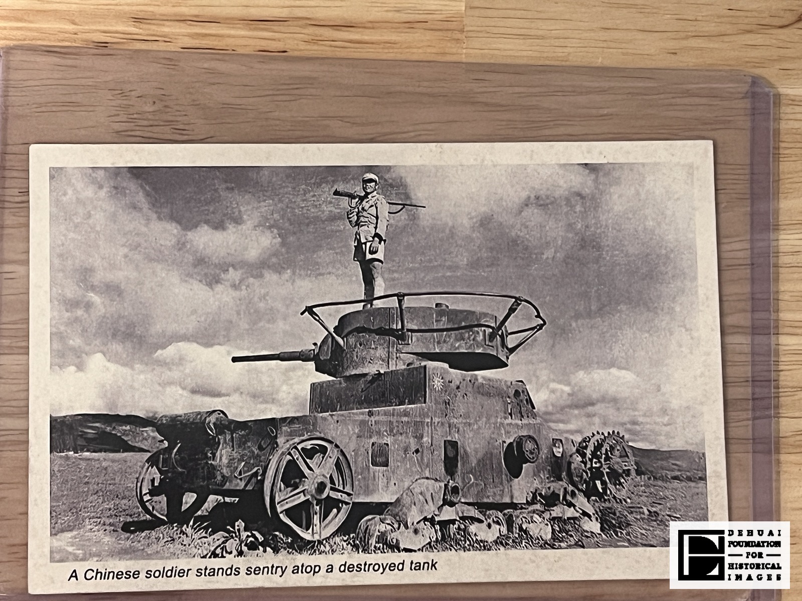 TFA-CA-120 — Face of the card: the reproduced photograph of a soldier standing on a derelict tank, with the single printed caption line below it.