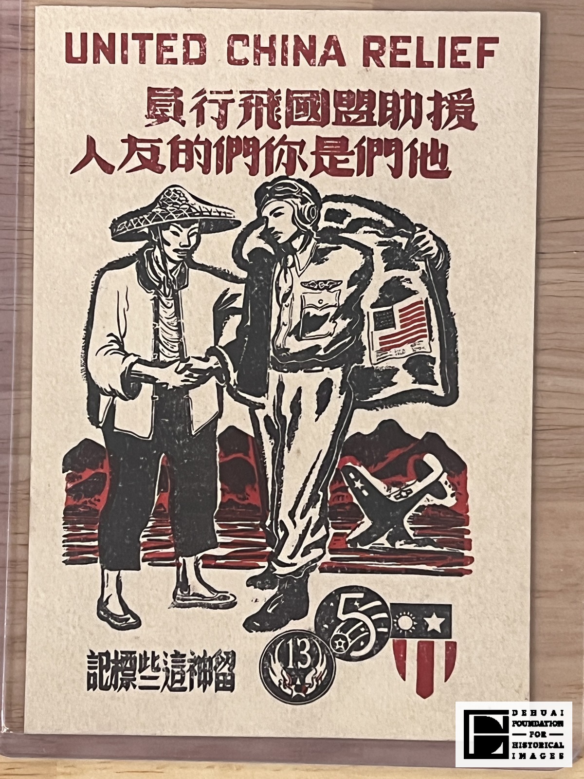TFA-CA-134 — Face of the sheet, photographed in its sleeve: the English heading 'UNITED CHINA RELIEF' above two lines of Chinese, the two men shaking hands, a further Chinese line at lower left, and the three service insignia at lower right.